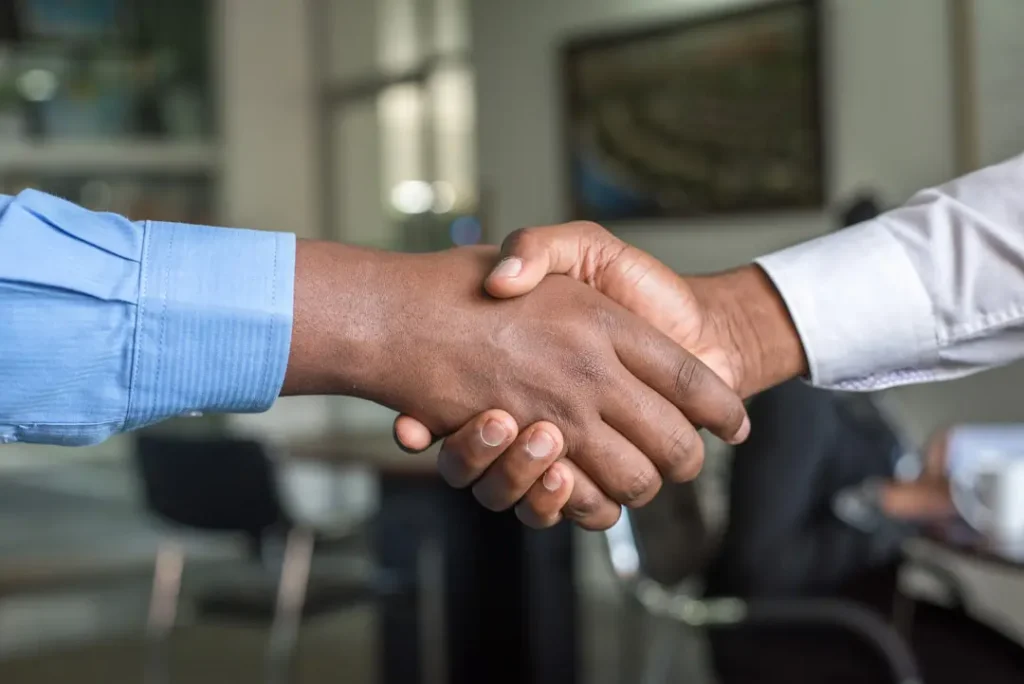 A salesman and his client shake hands after closing a deal.